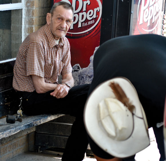 A customer waits on the bench outside Henderson Oil & Propane as employee Michael Pennington puts the lug nuts back on a tire he has just repaired. The full-service station was scheduled to convert to self-serve on Thursday, and they are also getting out of the tire and battery business.
